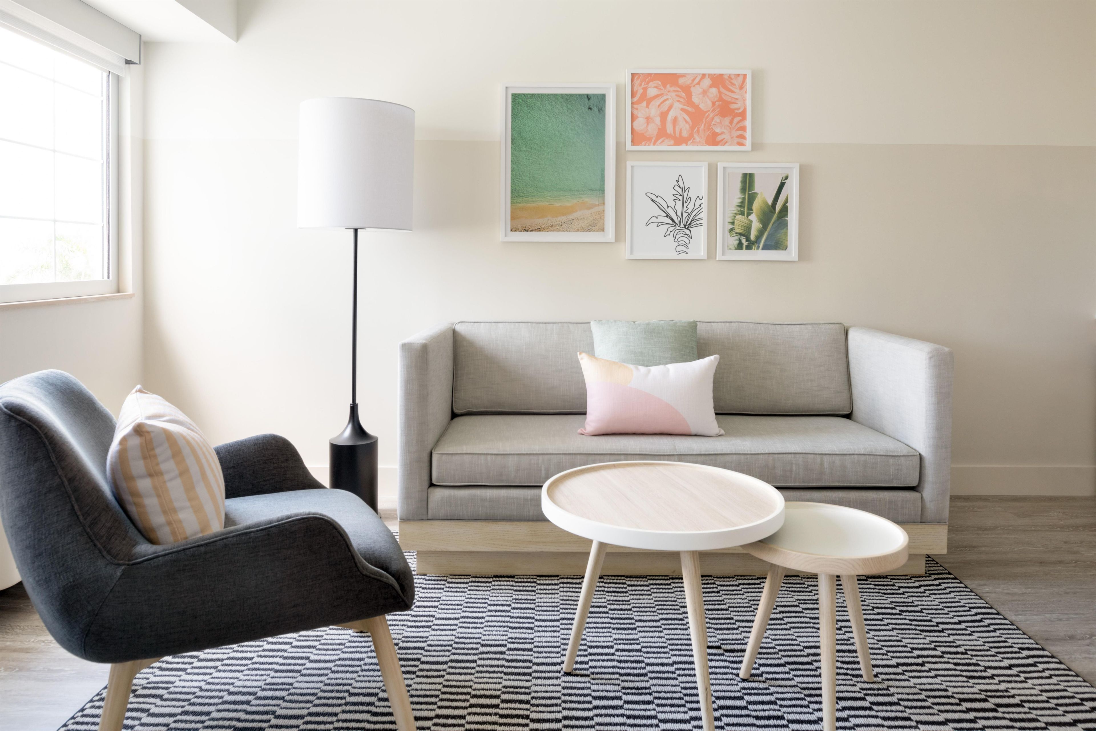 Una sala de estar moderna con un sofá gris, una mesa de centro redonda y una lámpara de pie.