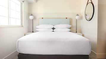 A neatly made bed with white linens, a light blue headboard, and two bedside lamps.