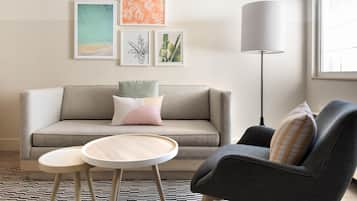 A living room with a sofa, two side tables, a floor lamp, and wall art.