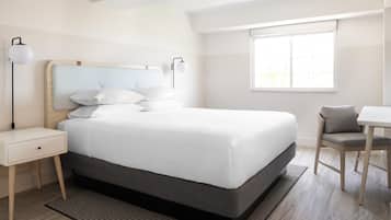 A modern hotel room with a large bed, bedside tables, a desk, and a chair.