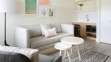 A modern living room with a grey sofa, two small round tables, and a patterned rug.