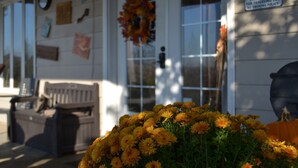 A building exterior with a porch, a bench, and a flower arrangement.