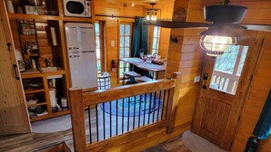 Ein gemütliches Blockhauss-Interieur mit einer Holzdiele, einem Essbereich und einer Küche mit Kühlschrank und Regalen.
