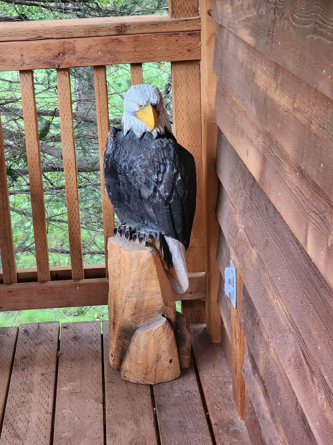 A wooden sculpture of a bird perched on a wooden post.