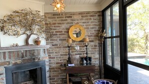 A cozy room with a brick fireplace, a large window, and a star-shaped light fixture. - Water views & only 2 miles to downtown  (Charleston)