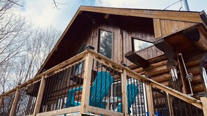 A wooden cabin with a balcony, large windows, and a chimney.