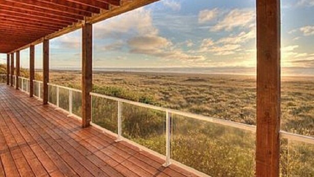 Eine Holzterrasse mit Geländer, die auf eine weite Landschaft blickt.