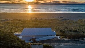 Ein Küstengebäude mit flachem Dach, direkt am Strand gelegen und mit Blick aufs Meer.