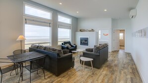 Ein großzügiger Wohnbereich mit großem Fenster zum Strand, Kamin und modernem Interieur.