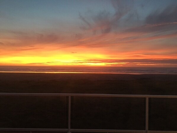 A sunset over a flat landscape with a railing in the foreground. - True Beachfront! 4BR, 4BA with amazing views and direct beach access. Hot Tub! (Moclips)