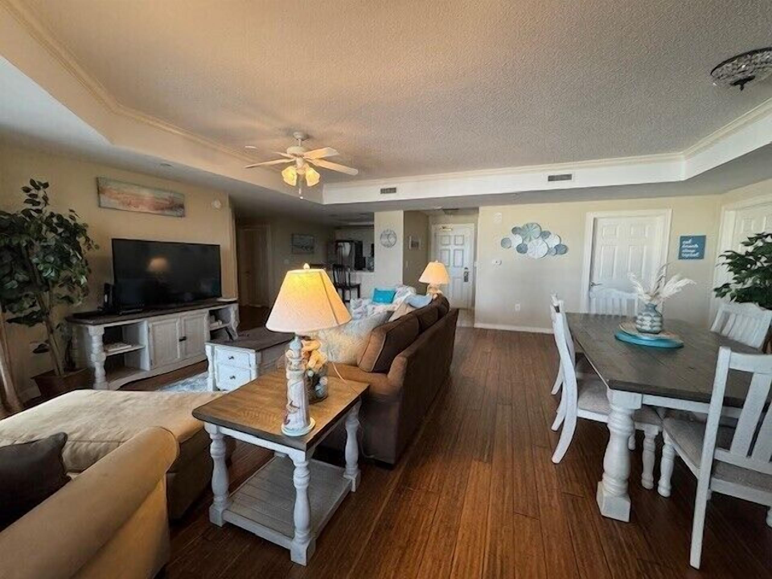 A spacious living room with a television, two lamps, a sofa, and a dining table with chairs.