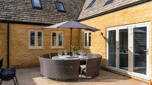 A patio with a round table, chairs, and an umbrella. - Maple House - sleeps 9 guests  in 5 bedrooms (Ebrington)