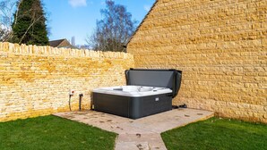 A hot tub in a backyard with stone walls and a grassy lawn. - Maple House - sleeps 9 guests  in 5 bedrooms (Ebrington)