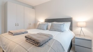 A bedroom with a bed, two bedside tables, a wardrobe, and a lamp. - Maple House - sleeps 9 guests  in 5 bedrooms (Ebrington)