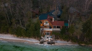 A large house with multiple levels, surrounded by dense forest. - Waterfront Escape at the Tip of Door County (Ellison Bay)