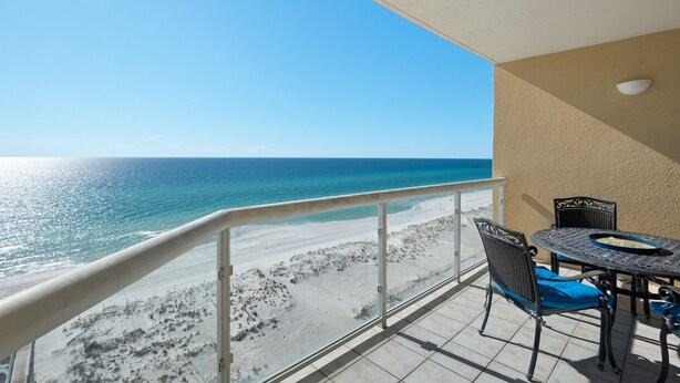 A balcony with a view of the beach and ocean.