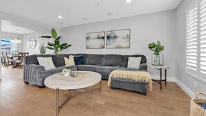 A modern living room with a grey sectional sofa, a round coffee table, and two large abstract paintings on the wall.