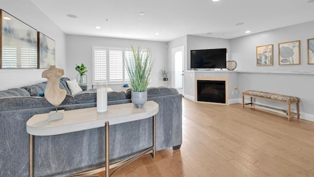 A modern living room with a grey sectional sofa, a wooden coffee table, a flat-screen TV, a fireplace, and a bench.