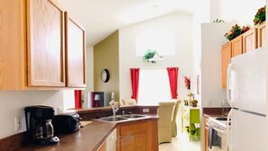 A kitchen with wooden cabinets, a coffee maker, a sink, and a refrigerator. - Gated Community - Southern Dunes Golf & Country Club - Private Pool (Haines City)