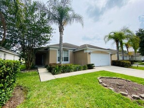 A residential house with a front yard, a driveway, and a garage. - Gated Community - Southern Dunes Golf & Country Club - Private Pool (Haines City)
