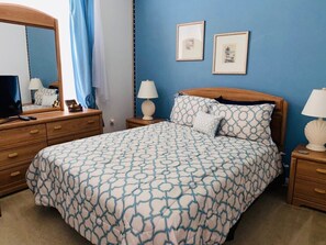 A bedroom with a bed, wooden nightstands, a dresser, a mirror, and two framed pictures on the wall. - Gated Community - Southern Dunes Golf & Country Club - Private Pool (Haines City)