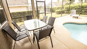 A covered patio with a pool, outdoor seating, and a glass table. - Private Pool - WiFi - Southern Dunes (Haines City)