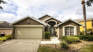 A residential house with a garage, a front door, and a driveway. - Private Pool - WiFi - Southern Dunes (Haines City)