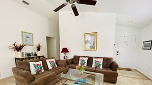 A living room with two brown sofas, a glass coffee table, and a ceiling fan. - Golf Course Views - Private Pool - WiFi - Southern Dunes Golf & Contry Club (Haines City)