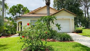 A single-story house with a garage, surrounded by a well-maintained lawn and various plants. - Golf Course Views - Private Pool - WiFi - Southern Dunes Golf & Contry Club (Haines City)