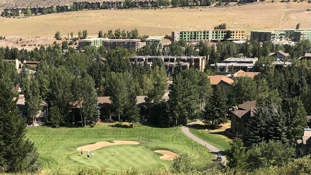 Un campo da golf con un club house e edifici residenziali sullo sfondo.