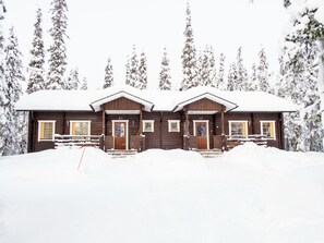 A wooden cabin with a snow-covered roof, surrounded by trees. - Villa jaloranta a by Interhome (Kuusamo)