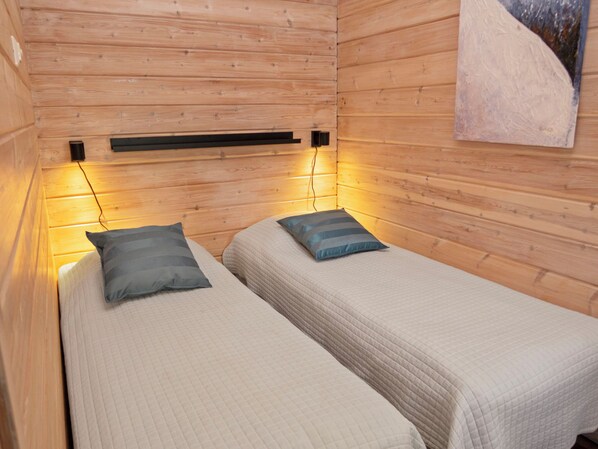 A room with two beds, each with a pillow and a headboard.