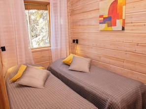 Una habitación con dos camas, una ventana con cortinas y un cuadro en la pared.