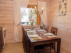 A wooden dining room with a table set for four, a chandelier, and a window with curtains.