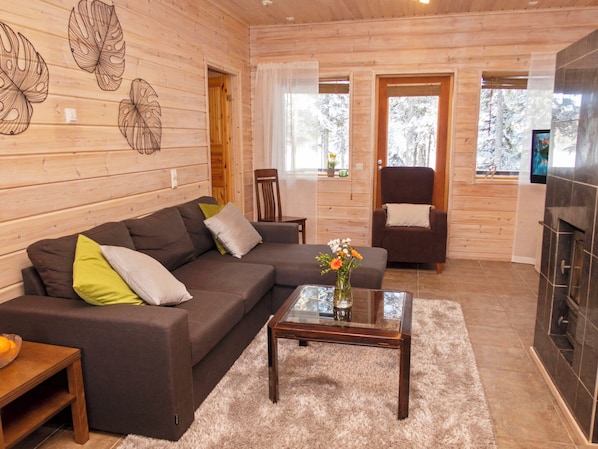 A modern living room with a sectional sofa, a glass coffee table, and a fireplace.