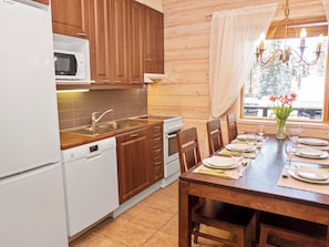 Una cocina con armarios de madera, un lavavajillas blanco, una estufa y un comedor listo para una comida.