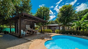 A swimming pool with a stone deck, a wooden pergola, and a hammock. - Luxury villas Playa Avellanas (Guanacaste)