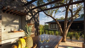 A wooden table with a fruit bowl containing bananas, pineapple, and limes, and two glasses of white wine. - Luxury villas Playa Avellanas (Guanacaste)