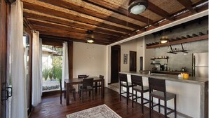 A modern kitchen with a bar area, wooden flooring, and a large window overlooking a garden. - Luxury villas Playa Avellanas (Guanacaste)