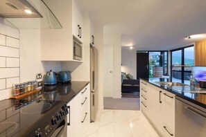 Une cuisine moderne équipée d’une cuisinière, d’un four à micro-ondes et d’un réfrigérateur. De grandes fenêtres offrent une vue sur l’extérieur.