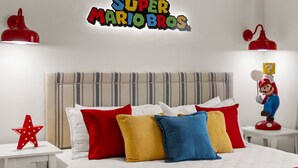 Une chambre à coucher avec un lit, des oreillers, une figurine de Mario et un panneau décoratif au mur.