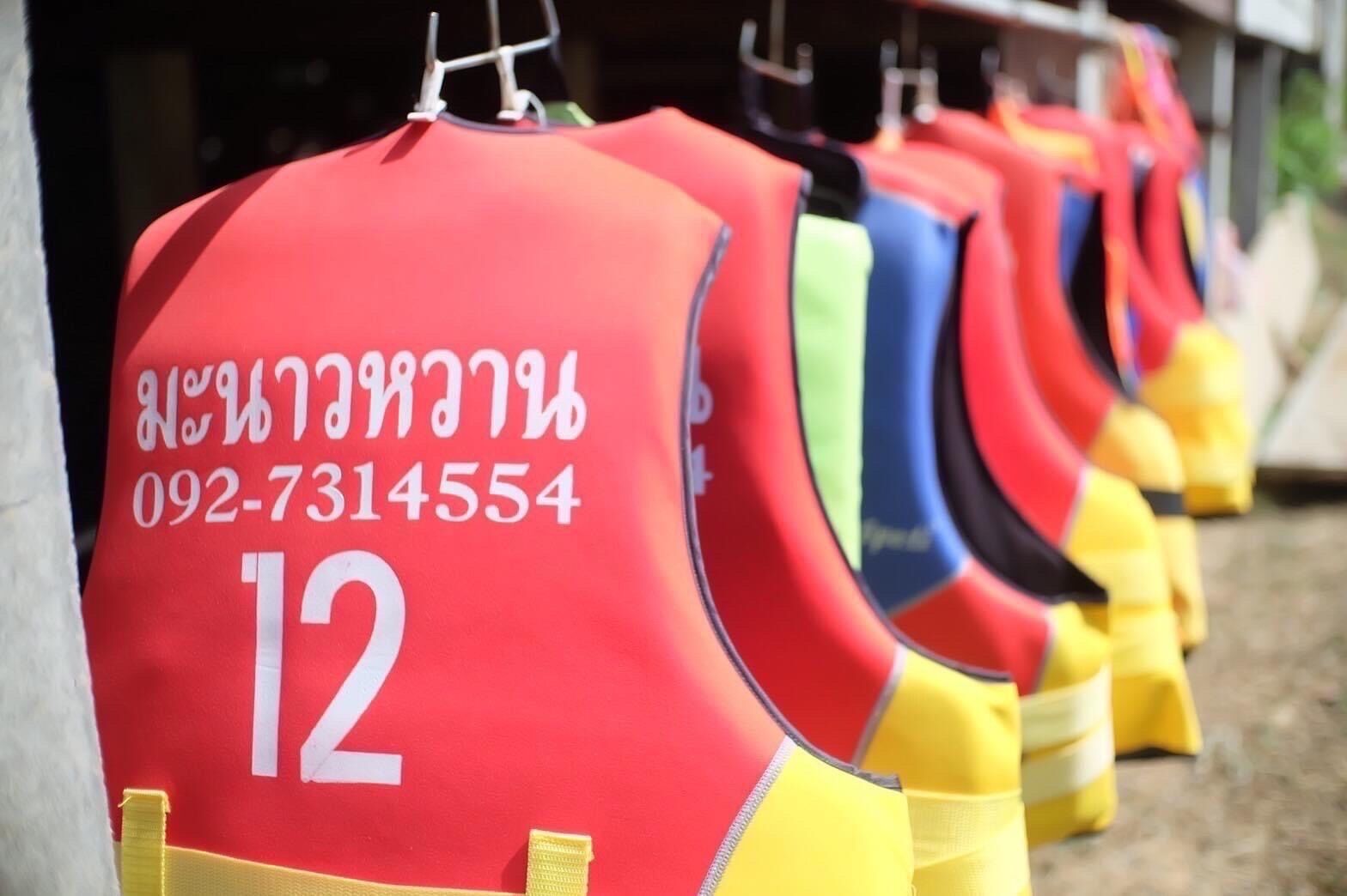 Una fila di giubbotti di salvataggio numerati appesi a ganci.
