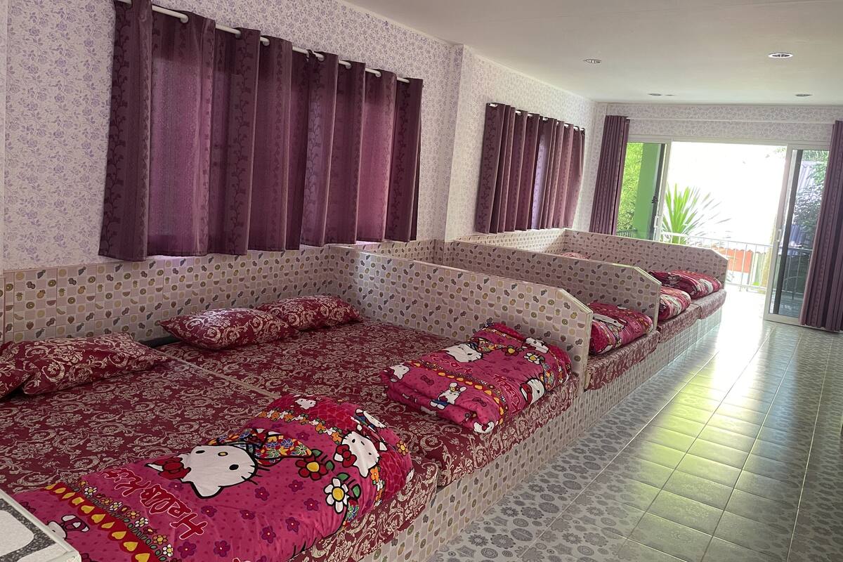Un long canapé étroit, doté de coussins à motifs, un mur également orné de motifs et une vue sur l’extérieur grâce à une porte coulissante.