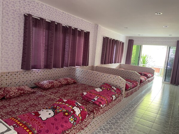 Un sofá largo y estrecho con cojines estampados, una pared con diseño y vistas al exterior a través de una puerta corrediza.