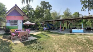 Un edificio colorido con un parque infantil y zona de picnic.