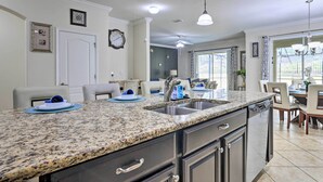 A modern kitchen with granite countertops, stainless steel appliances, and a dining area with a chandelier. - Paradise Palms Home w/ Pool, 6 Mi to Disney! (Kissimmee)