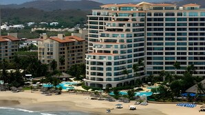 A high-rise hotel with multiple balconies, a beach, and a pool area. - 302 S Bay View Grand Residencial Ixtapa (Ixtapa)