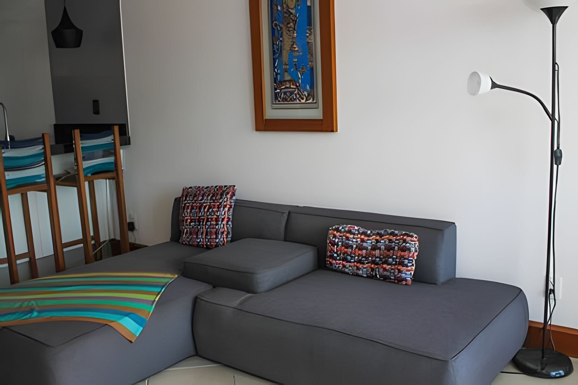 Una sala moderna con un sofá seccional gris, una manta a rayas colorida y almohadones estampados.