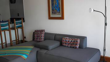 Una sala moderna con un sofá seccional gris, una manta a rayas colorida y almohadones estampados.