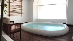 A hot tub on a wooden deck with a bamboo wall and a chair. - 302 S Bay View Grand Residencial Ixtapa (Ixtapa)